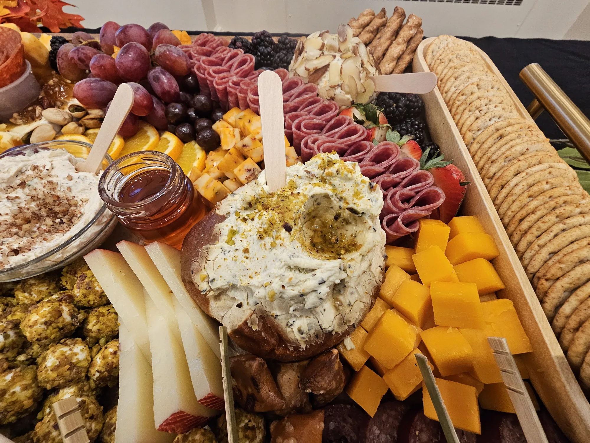 Close-up of a charcuterie board with salami, cheese, whipped dip, and fresh fruit
