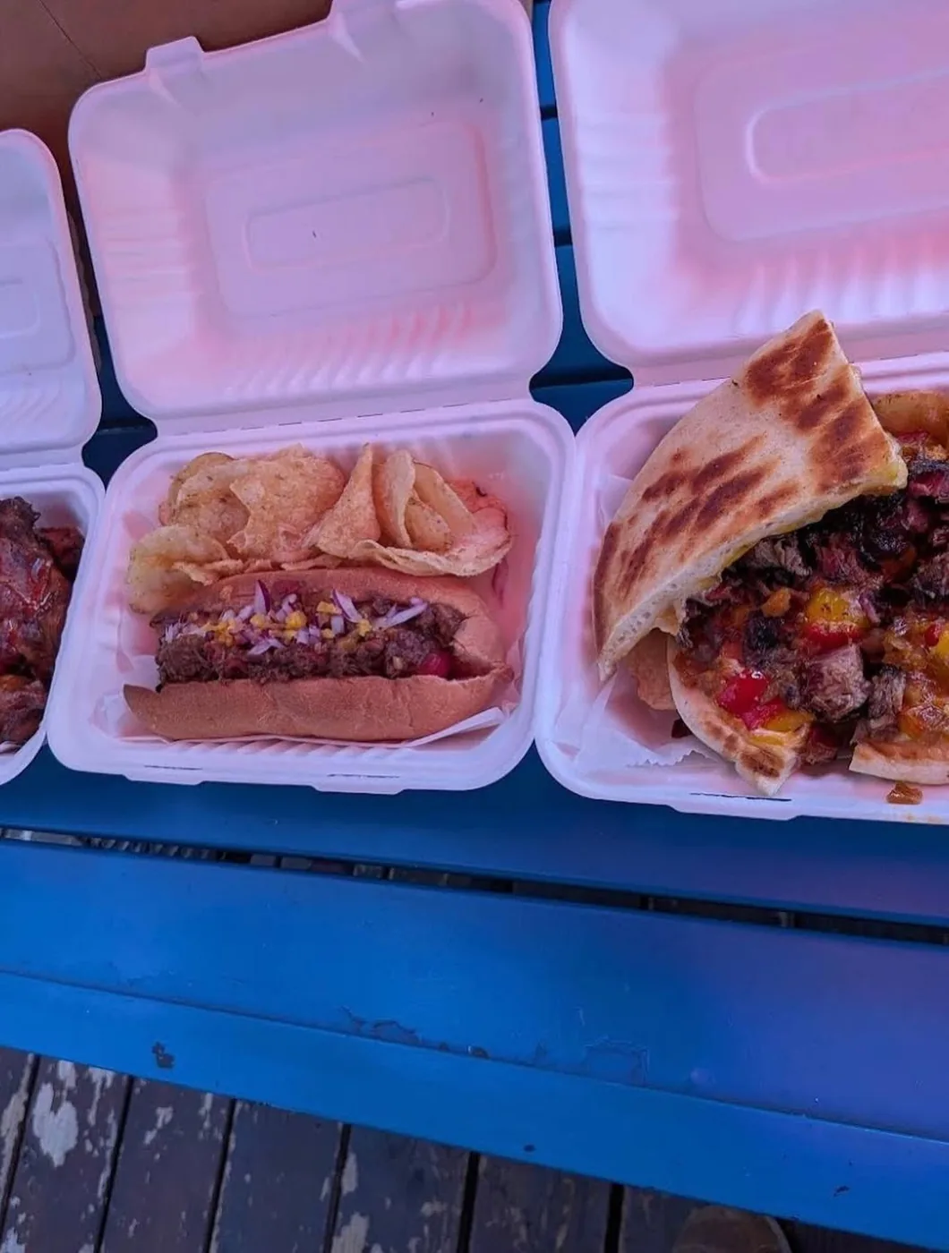 Two takeout containers from Global Fusion RVA's food truck, holding a hot dog and a grilled sandwich
